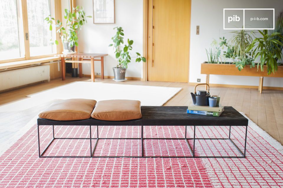 Large black wooden and metal bench with light leather cushions.