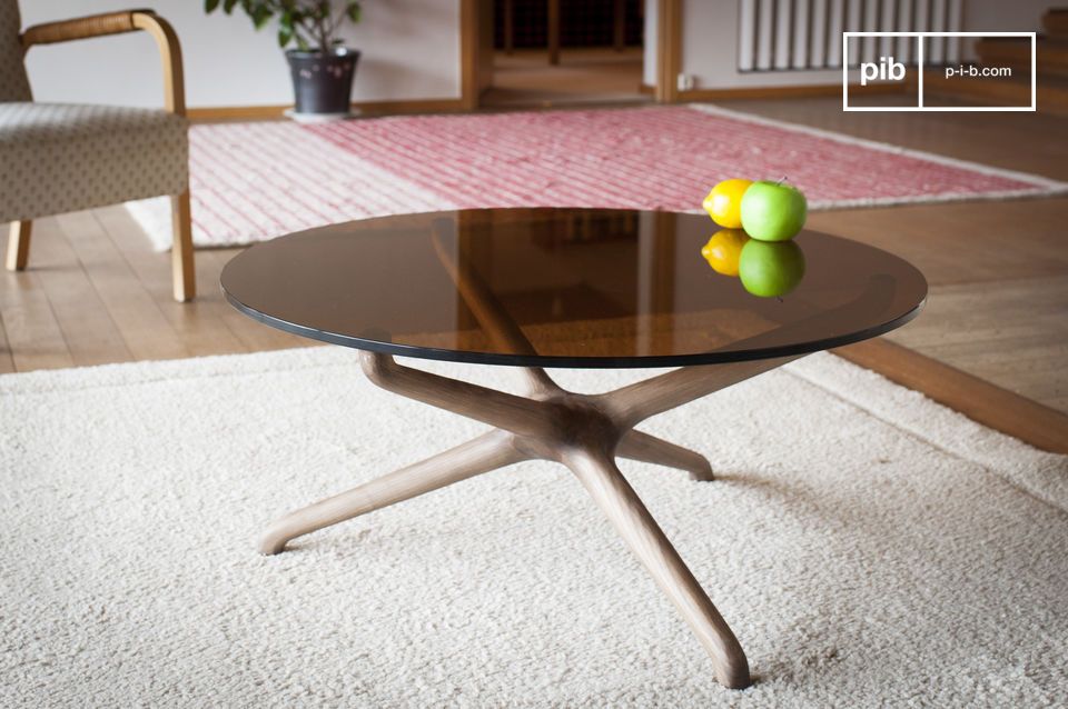 The roundness of a low table in smoked glass and carved wood