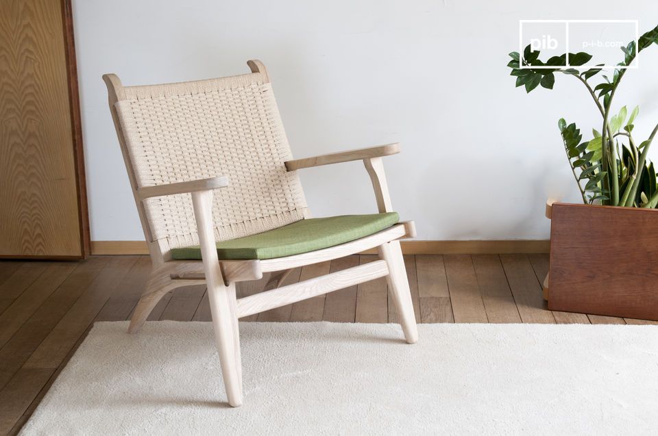 A natural armchair combining blond wood, woven rattan and olive green color.