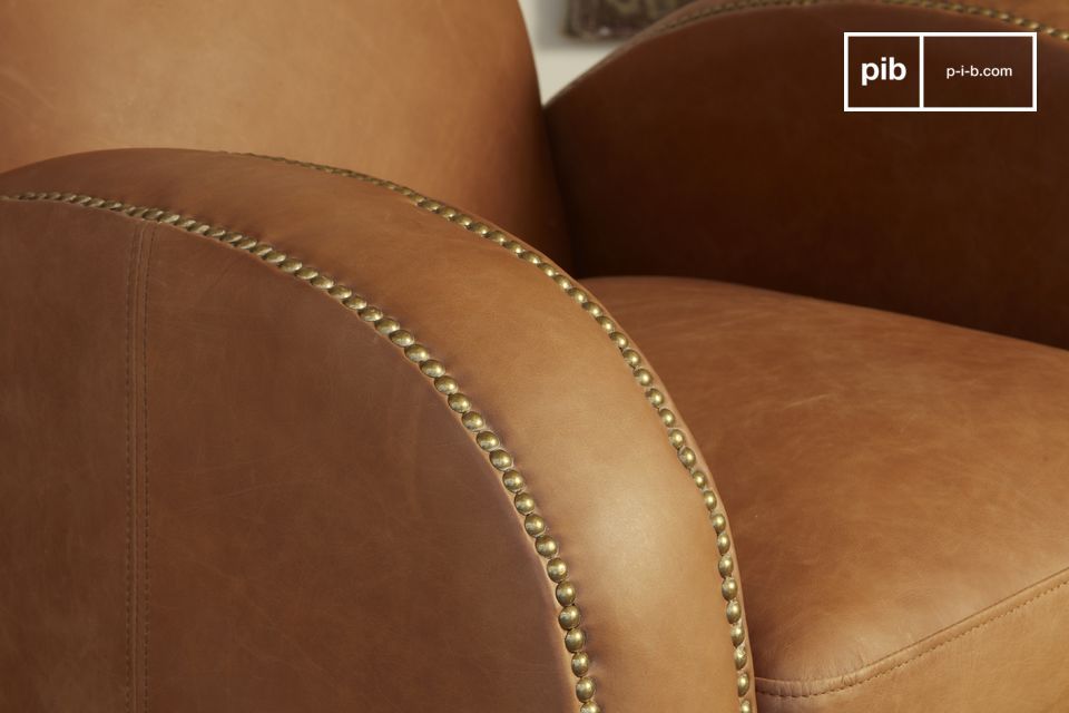 The camel tones of the armchair are enhanced by a brushed brass nailing work.
