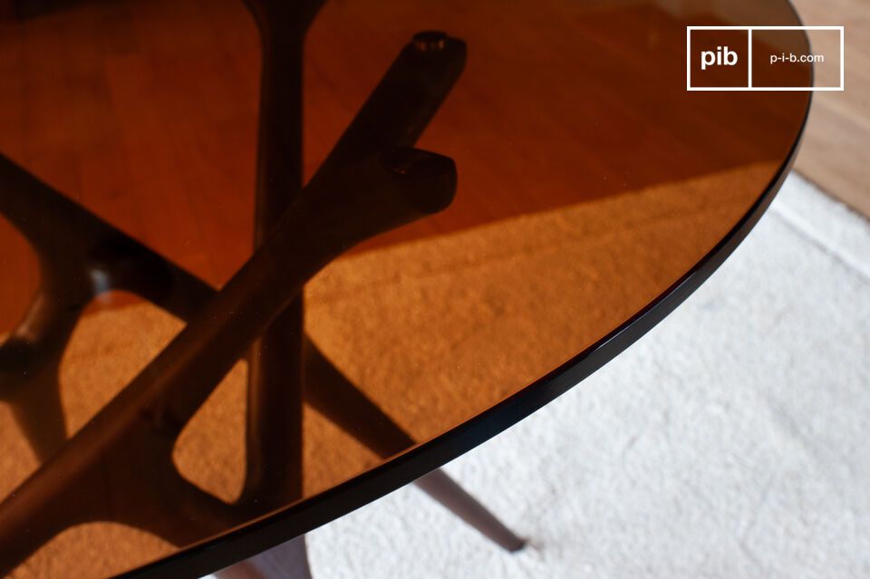 Its smoked glass tabletop rests on a sculptural base that evokes intertwined natural lines